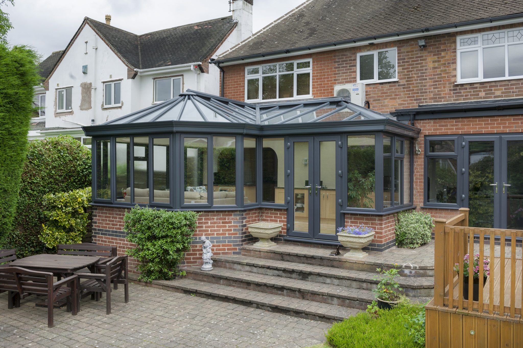 Bespoke conservatory style with charcoal colour frames and red brick finish.